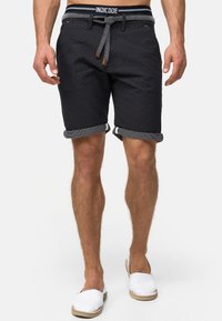 Marineblå shorts med et tekstureret stof, oprollende manchetter og et kontrasterende elastisk livbånd med logo. Designet med snorelukning.