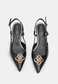 Črne lakirane slingback petke s zašiljenimi prsti, ki imajo na sprednji strani zlato dekorativno vozlišče in oblazinjen črn podplat.