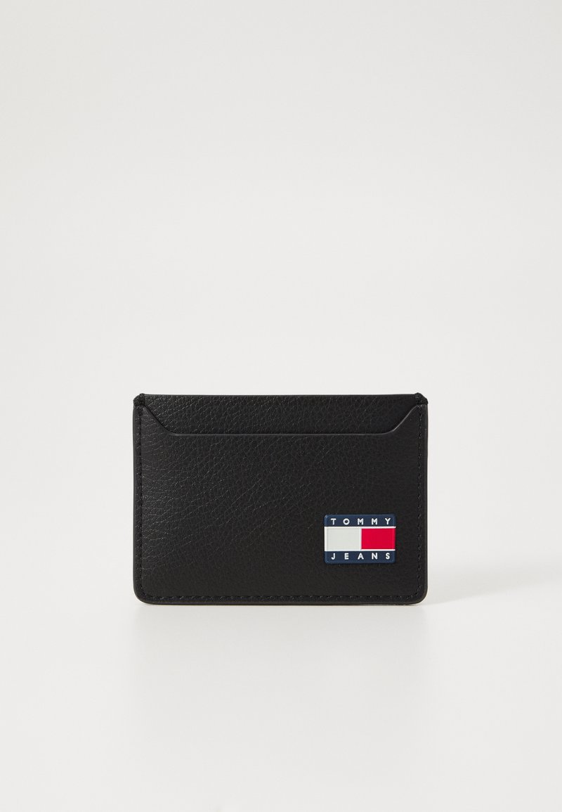 Carteira de couro preta com superfície texturizada, duas ranhuras para cartões e um logótipo decorativo com acentos em vermelho, branco e azul.