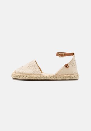 Zapato plano de esparto beige con bordado floral, suela de yute y correa marrón en el tobillo con hebilla dorada sobre fondo blanco.