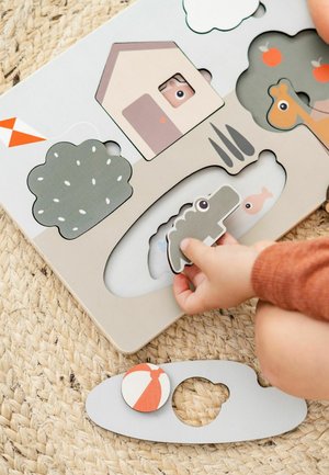 Puidust pusle, millel on värvikirevad loomakujud, sealhulgas krokodill. Omab helehall-tahvlit, lõigatud kujundusi ja tekstuuriga tausta.