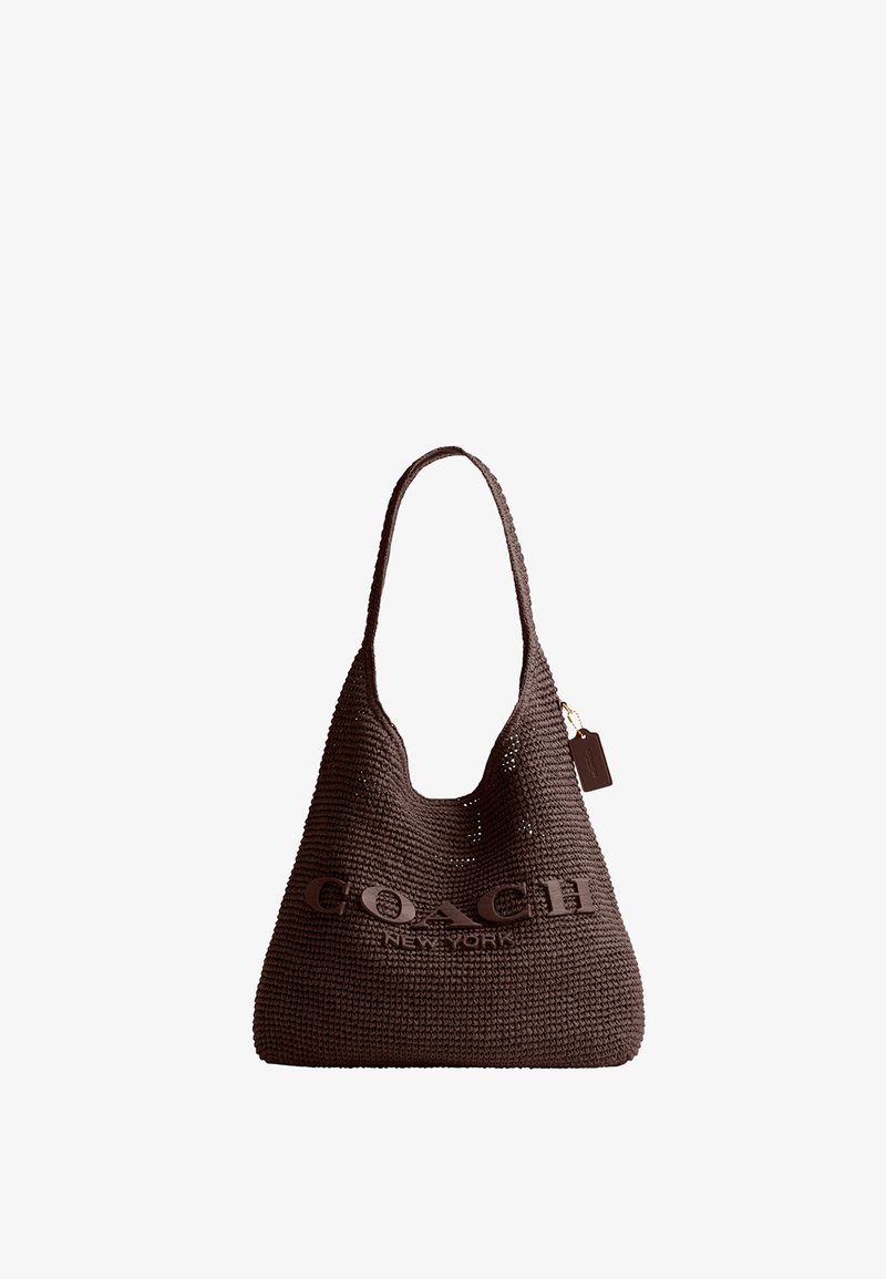 Sac fourre-tout tressé marron avec une seule bandoulière et une étiquette, présentant l'inscription "COACH NEW YORK" en relief sur le devant.