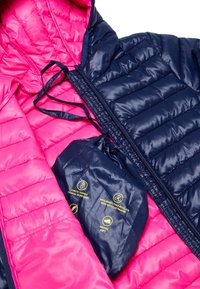 Padded jacket z różowym wnętrzem i granatowym zewnętrzem. W zestawie pasująca torba pakowna z instrukcjami pielęgnacji wydrukowanymi na żółto.