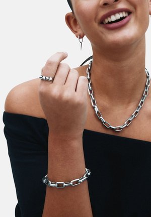 Biżuteria srebrna z masywnym łańcuchem naszyjnika, pasującą bransoletką i wzorzystym pierścionkiem. Gładka tekstura z polerowanym wykończeniem.