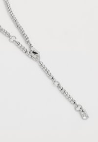 Collier en perles argentées composé de perles rondes, d'un fermoir à ressort et d'un petit tag avec des détails gravés. Texture lisse et finition métallique.