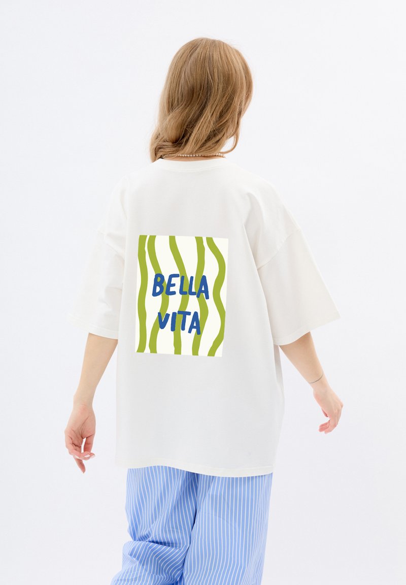 Witte oversized t-shirt met groen en wit gestreepte grafiek op de achterkant met de tekst "BELLA VITA" in het blauw.