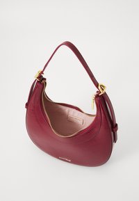 Maroon leather handbag with a curved shape, gold zipper, and a single strap. Interior lined with light fabric, featuring a brand label.