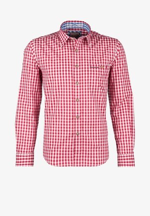 Homme portant un lederhosen en cuir marron traditionnel avec des bretelles, une chemise à carreaux rouge et blanc, des chaussettes grises et des chaussures noires.