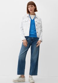 Weiße Jeansjacke, blauer Strickpullover mit strukturiertem Muster, lässige blaue Jeans und beige Sneakers. Einfaches und lässiges Outfit.