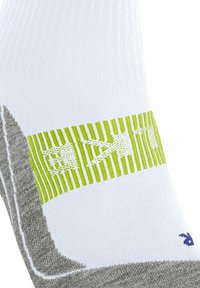 Calcetín blanco y gris con una banda verde a rayas audaces y diseños gráficos en blanco. El material parece transpirable, con textura acanalada y punta reforzada.