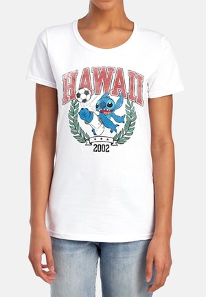 Person wearing a white t-shirt with "HAWAII" text, a blue cartoon character playing soccer, green laurel leaves, and "2002" below.
