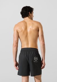 Muške crne kupaće gaće s elastičnim pojasom, stražnjim džepom i izvezenim logotipom. Glatki materijal s laganim dizajnom.