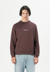 Brun crewneck sweatshirt laget av bomull med ribbede mansjetter og kant. Har hvit brodert tekst på brystet. Avslappet passform.