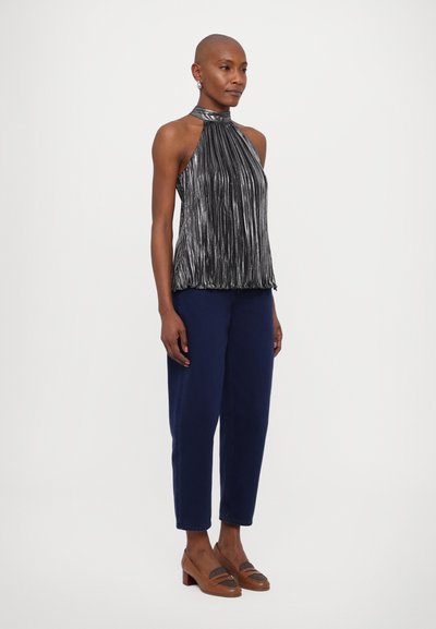 Metālisks halter tops ar vertikālām krokām, kombinēts ar tumši ziliem sašaurinātiem biksēm un brūniem bloku papēžiem. Gluda tekstūra un elegants dizains.