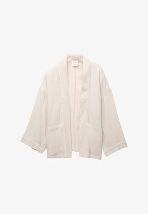 Kimono bej deschis, cu mâneci late, realizat dintr-un material texturat. Are două buzunare frontale și un design deschis în față.