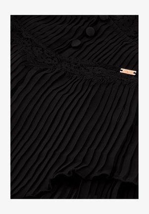 Sort plisseret stof med blonder, to runde knapper og et lille metallskilt. Tekstur overflade med et flydende design og flæset kant.