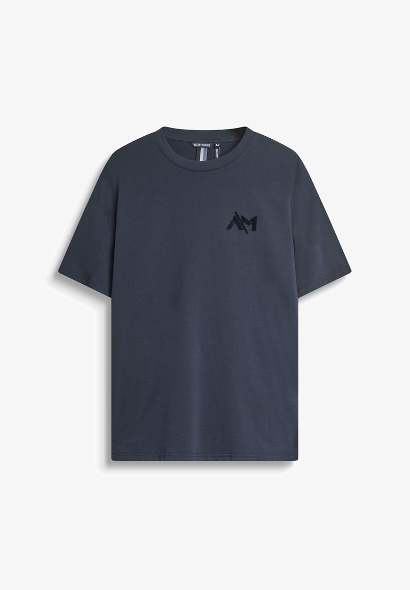 Camiseta de algodón azul marino de manga corta, con cuello redondo y detalle de logo en la parte frontal en un tono ligeramente más oscuro. Textura suave, ajuste casual.