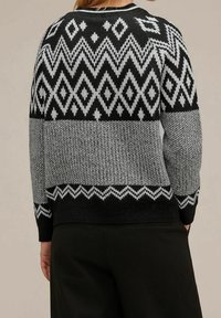 Svart och grå stickad tröja med geometriska mönster, som har zigzag- och diamantmotiv. Ribbad muddar och nederkant, rundad halsdesign.