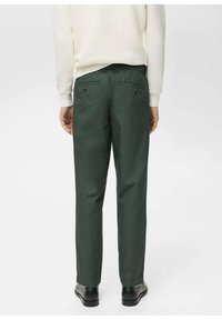 Green chinos made from cotton blend fabric, featuring a straight cut, two back pockets with buttons, and a relaxed fit.