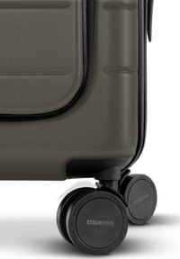 Grauer Hartschalenkoffer mit strukturierter Oberfläche, ausgestattet mit vier schwarzen Drehrollen und einem auffälligen Markenlogo auf der Rolle.