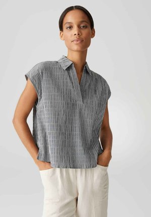 Camicia a maniche corte a righe con colletto, caratterizzata da linee verticali in colori scuri e chiari, tessuto leggero e vestibilità rilassata.