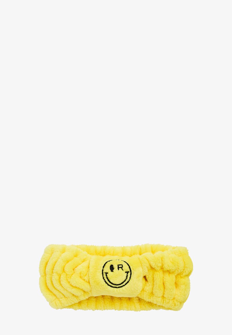 Bandeau tête en peluche jaune avec élastique froncé et visage souriant brodé avec les lettres "I R" en noir au centre avant.