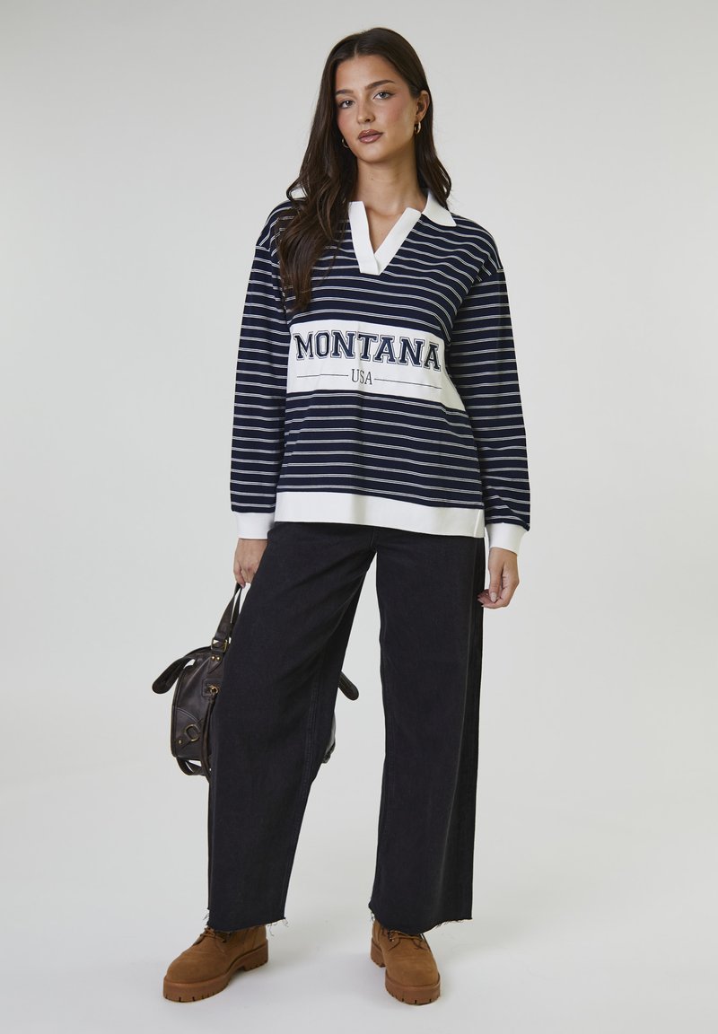 Maglietta a maniche lunghe a righe blu navy e bianche con colletto bianco e logo "MONTANA USA", abbinata a pantaloni neri a gamba larga e scarpe marroni.
