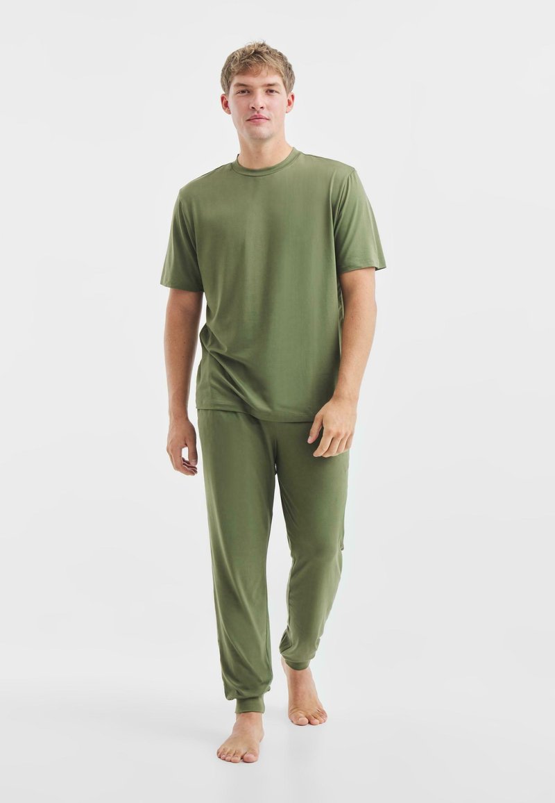 Set di abbigliamento da casa coordinato in verde oliva, composto da una maglietta a maniche corte e pantaloni jogger con polsini elasticizzati, realizzato in tessuto morbido.