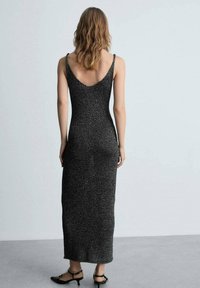 Vestito lungo nero e scintillante con sottili spalline e scollatura a V profonda, che mette in risalto una silhouette aderente e una trama liscia.