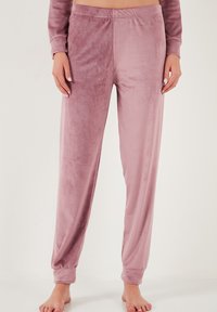 Bársonyos loungewear nadrág poros rózsaszín árnyalatban. Rugalmas derékpánttal, hosszú egyenes lábakkal és szoros mandzsettával a bokáknál rendelkezik. Puha tapintású.