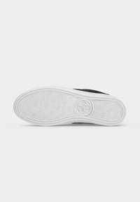 Semelle de chaussure en caoutchouc blanche avec motif texturé et logo circulaire au centre, vue de dessous.