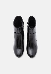 Musta pahkluu saapad, mis on valmistatud läikivast krokodillinahast, sileda viimistlusega ja külgsete tõmblukkudega mugavaks kandmiseks.