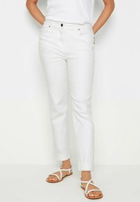 Pantalones rectos de algodón blanco con una cinturilla que presenta un cierre de botón, bolsillos laterales y puños doblados por encima del tobillo.