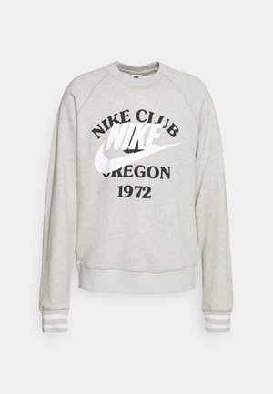 Světle šedá mikina s kulatým výstřihem, raglánovými rukávy, černým nápisem "NIKE CLUB OREGON 1972" a proužkovanými manžetami ve světle šedé a bílé barvě.