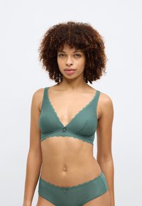 Bralette verde com acabamento de renda, em tecido texturizado e design em V, apresentando alças ajustáveis e um pequeno laço decorativo ao centro.