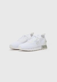 Baskets de sport blanches avec une tige en mesh texturé, un design à lacets et des accents gris clair sur la semelle. Présente un logo sur le côté et le talon.