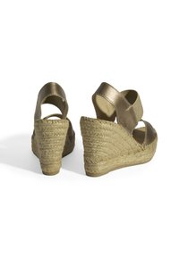 Sandales en bronze avec un dessus en tissu texturé et un talon en paille tressée, présentant un dos ouvert et des bandes élastiques pour un maintien sécurisé.