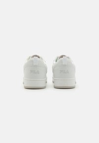 White leather sneakers with a textured finish, featuring a padded collar, flat laces, and a rubber sole. Brand logo embossed on the heel.