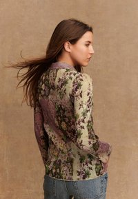 Bloemmotief shirt met een mix van groene en paarse strepen, gemaakt van een textuurstof en met een zachte kraag. Gestyled met blauwe spijkerbroek.