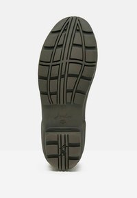 Tumed roheline kummist jalanõu tald sügavate jälgedega mustriga, millel on horisontaalsed ja vertikaalsed jooned ning kõrgendatud logo.