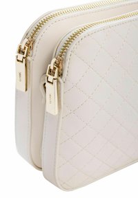 Dwupak z pikowanej białej skóry z złotymi zamkami błyskawicznymi i elementami metalowymi. Gładka faktura, zaokrąglone narożniki i subtelne detale przeszyć.