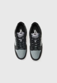 Nike sportcipők fekete és sötétszürke felsőrésszel, nubuk- és bőranyagokból, perforált orr résszel, fekete fűzőkkel és fehér középtalppal.