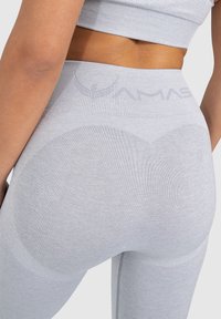 Leggings gris con relieve y una cintura alta, que presentan un diseño ajustado y un patrón texturizado sin costuras en la zona de las piernas.