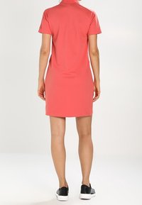 Koronkowa sukienka polo z krótkimi rękawami, kołnierzykowym dekoltem, prostym krojem i gładką fakturą, zestawiona z czarnymi sneakersami.