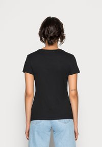 Svart bomullströja med korta ärmar och rund halsringning, med en slät yta och en figursydd design.