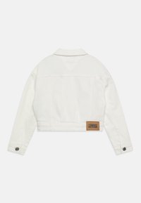 Giacca in denim bianca a taglio cropped con colletto a punta, polsini con bottoni e una toppa in pelle marrone sul retro. Tessuto testurizzato.