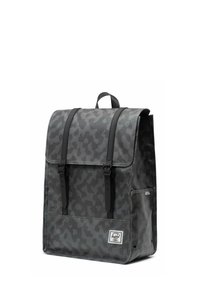 Sac à dos gris à motif camouflage avec un rabat de fermeture, des accents en cuir et des bretelles réglables. Dispose d'une poche avant et d'une texture en tissu.