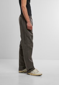 Grå sweatpants med snoretræk i taljen, sidelommer og en afslappet pasform, parret med beige sneakers. Glat stof, minimalistisk design.