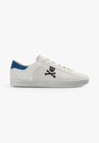 Zapatilla de ante blanca con un acento en el talón azul, que presenta bordado de calavera y huesos cruzados en el lateral y una suela de goma texturizada.