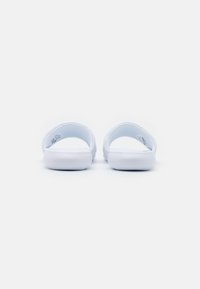 Hvite sandal med såle i teksturert materiale, myk innermateriale, og glatt gummisole. Designet har ingen dekorasjoner eller mønstre.